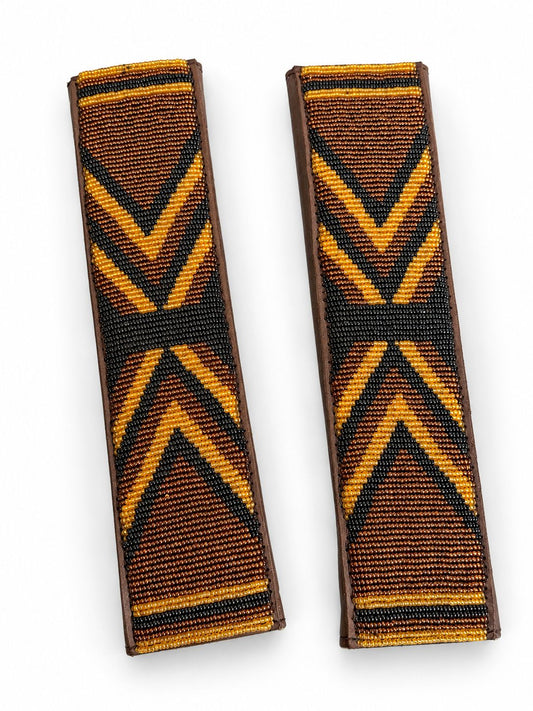 Two amber and black beaded seat belt covers at an angle, handmade in Kenya