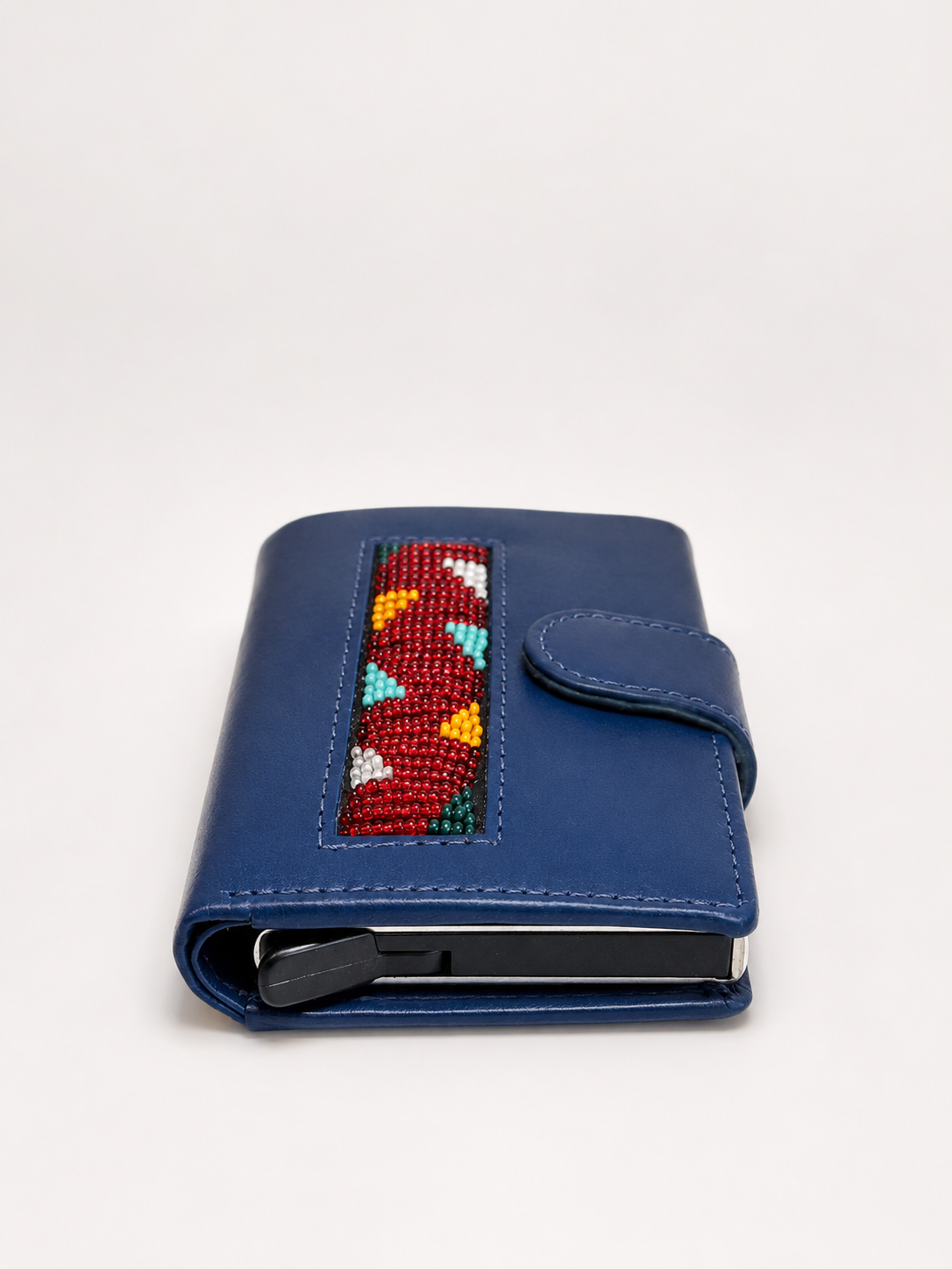 Side profile of blue handmade leather RFID wallet showing Maasai beadwork panel, card ejector and snap closure