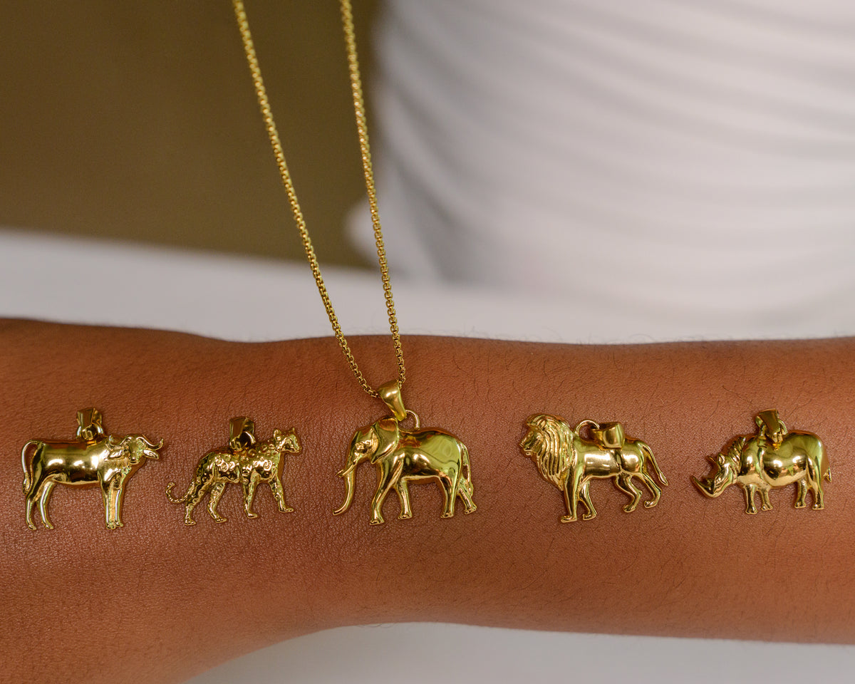 Model wearing gold-plated Big Five charm necklace with buffalo, leopard, elephant, lion and rhino charms lined up on the chain
