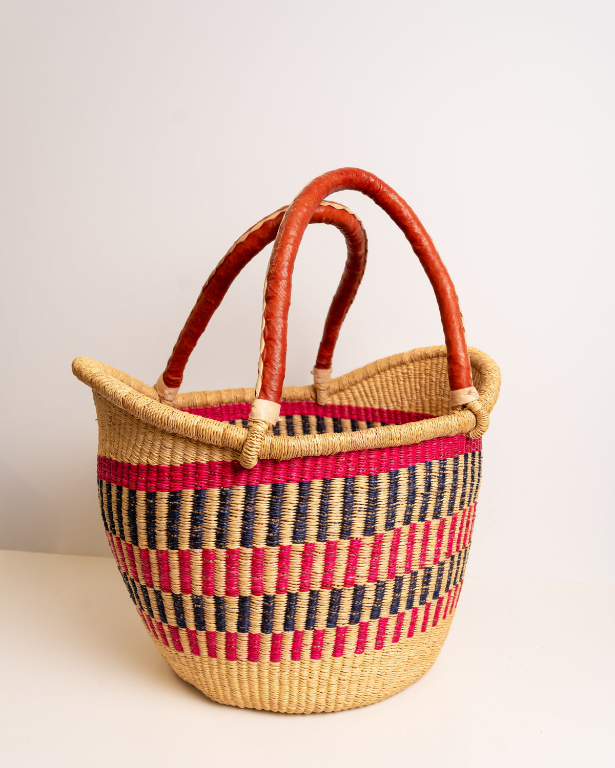 Woven basket with red and blue pattern on a light background