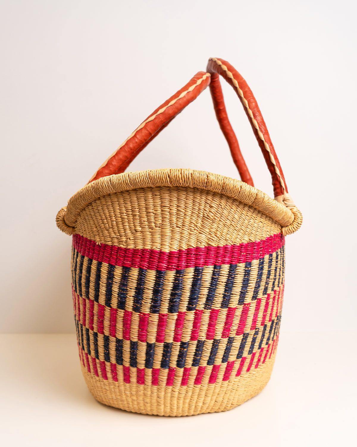 Woven basket with red and blue striped pattern on a white background