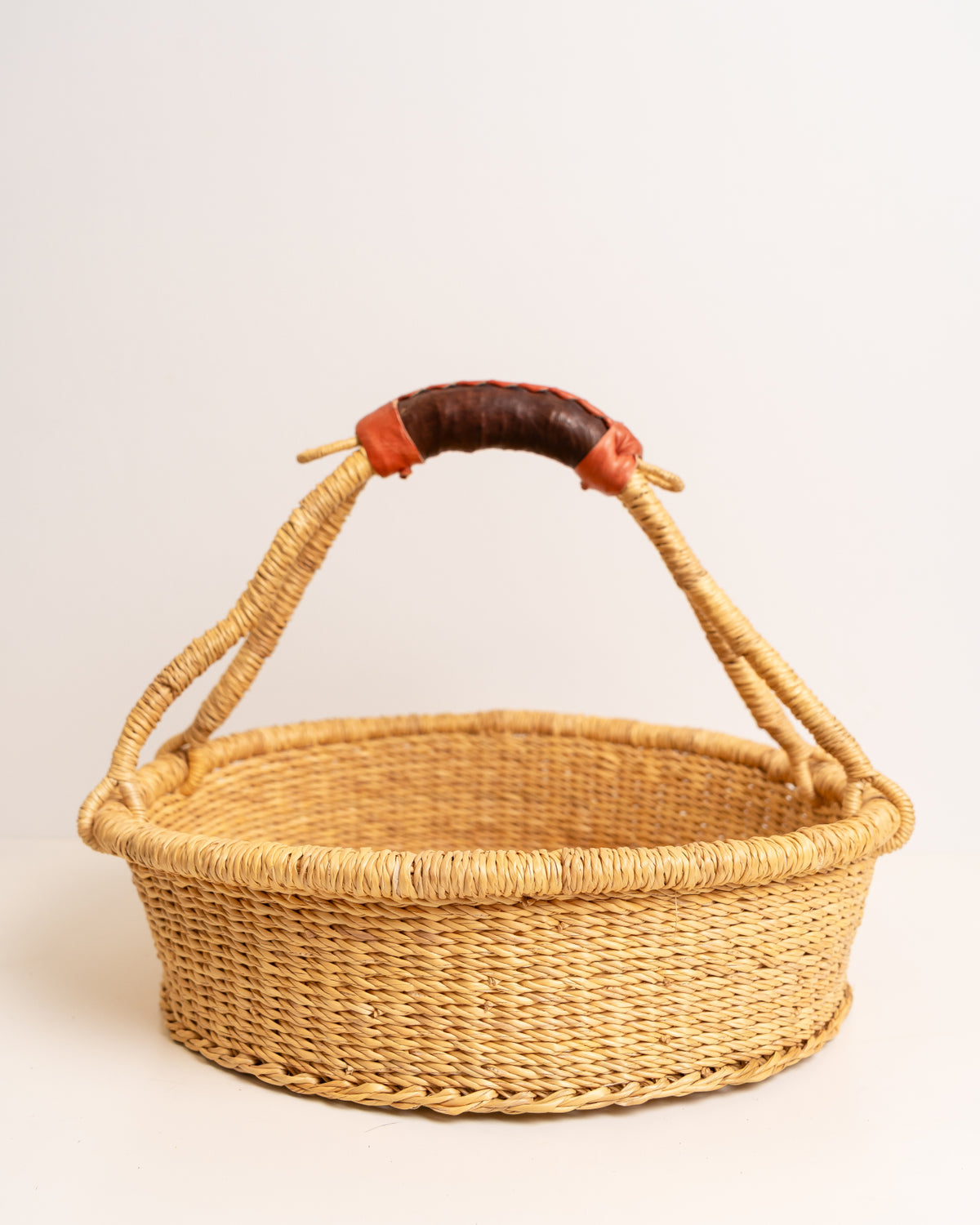 Handwoven Bolga tray basket with leather-wrapped handle, Ghana