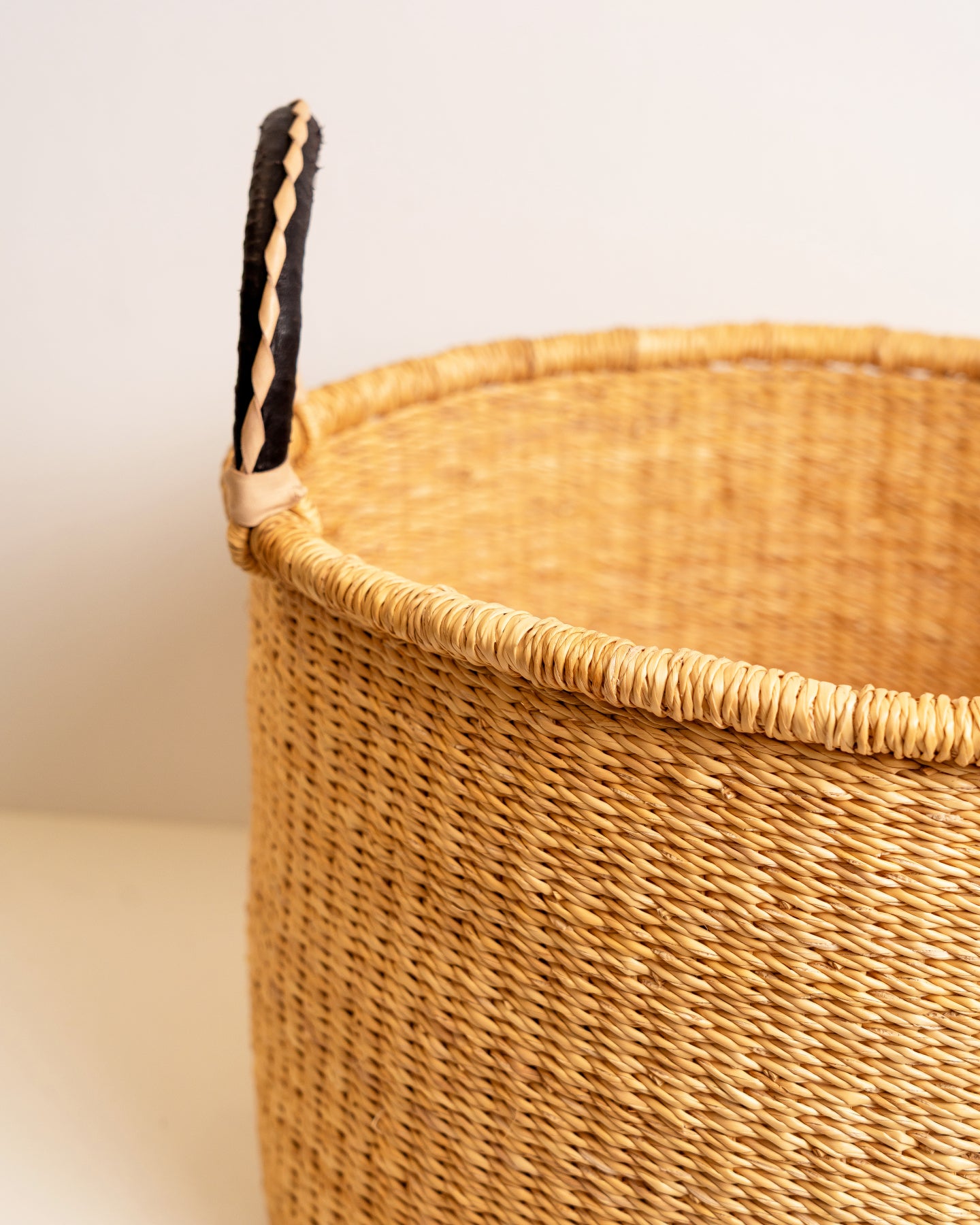 
Three-quarter view of a large handwoven elephant grass Bolga basket with dual leather handles, showing the wide open top and sturdy structure — Nathez Out of Africa