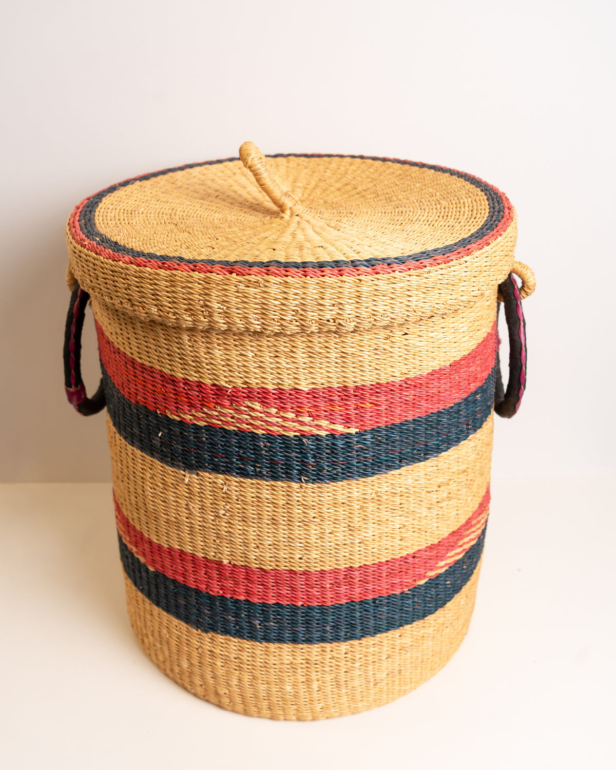 Handwoven Bolga laundry basket with lid closed, red and navy stripe - fair trade elephant grass storage hamper from Ghana