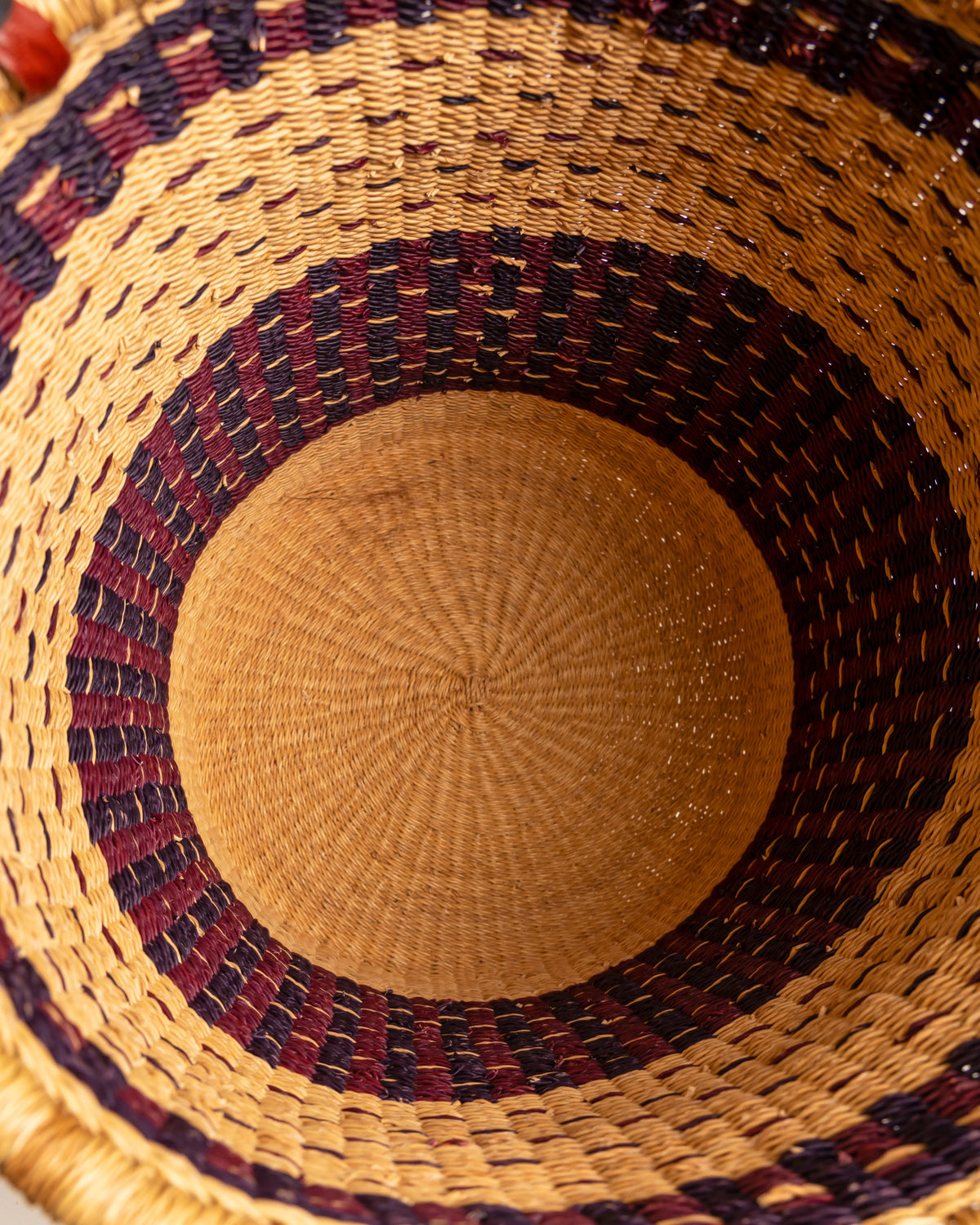 Inside view of small Bolga laundry basket base showing burgundy and tan woven pattern - handwoven elephant grass basket, Ghana