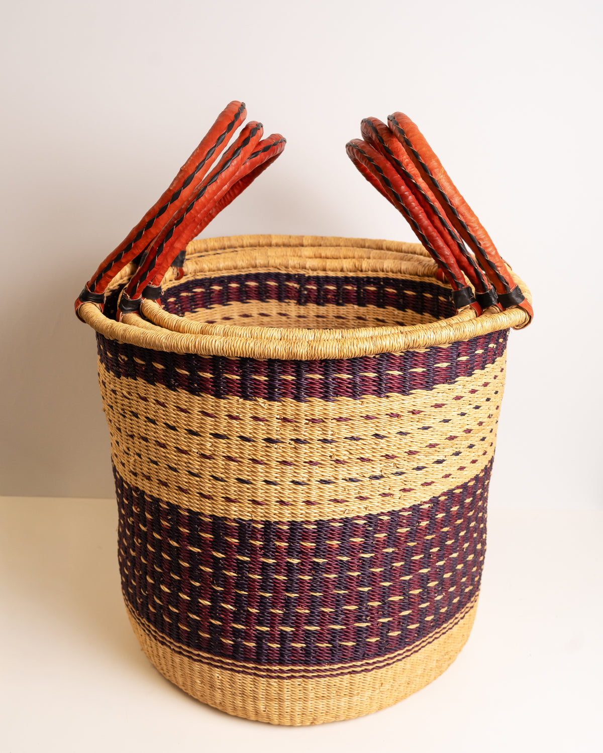 Open top view of small Bolga laundry basket in burgundy and tan stripe showing leather-wrapped handles - handmade elephant grass hamper, Ghana