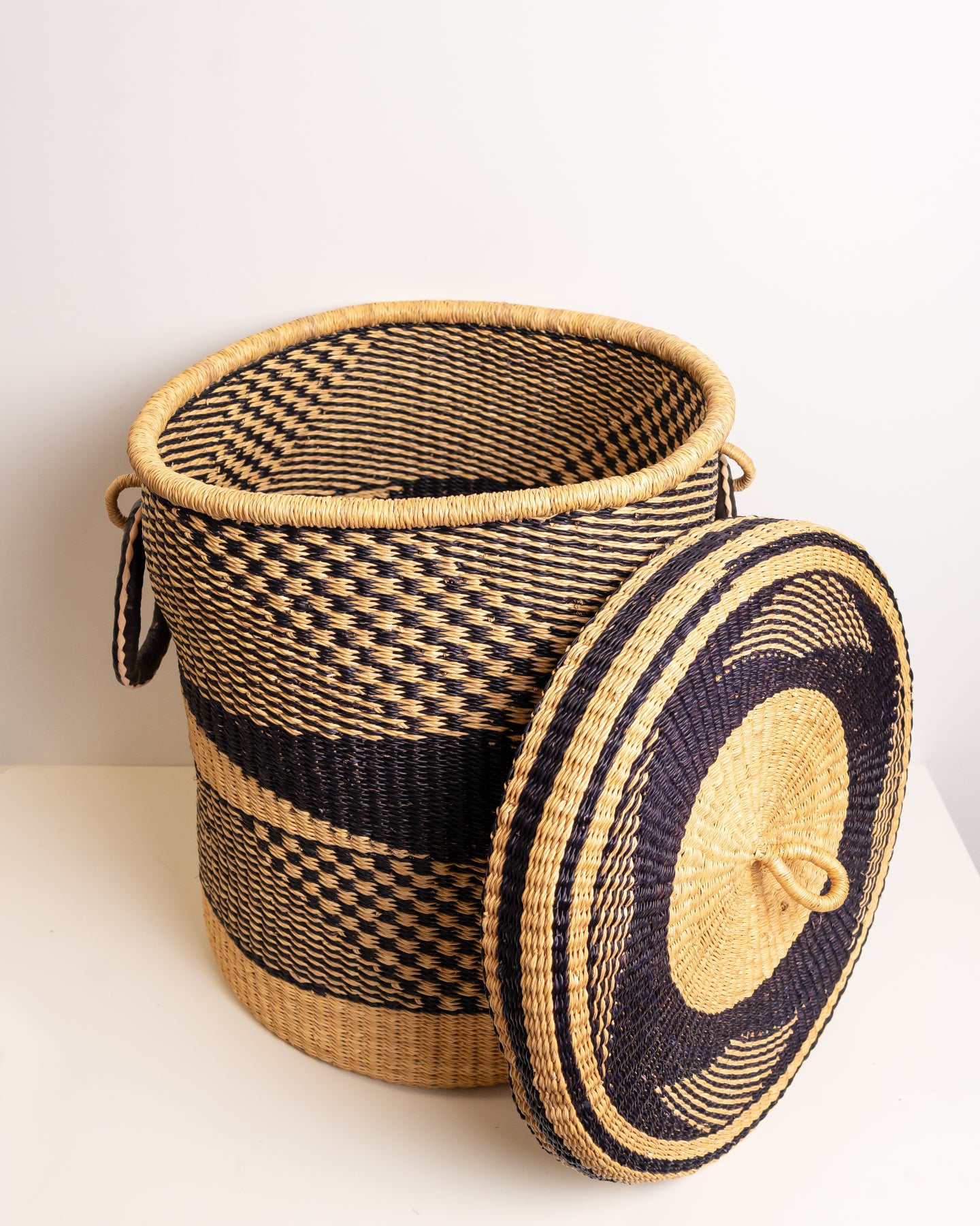 Handwoven Bolga laundry basket with lid resting beside it, African storage basket, Ghana