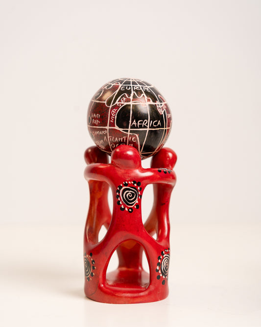 Hand-carved soapstone sculpture with red linked figures supporting a black and red world globe.