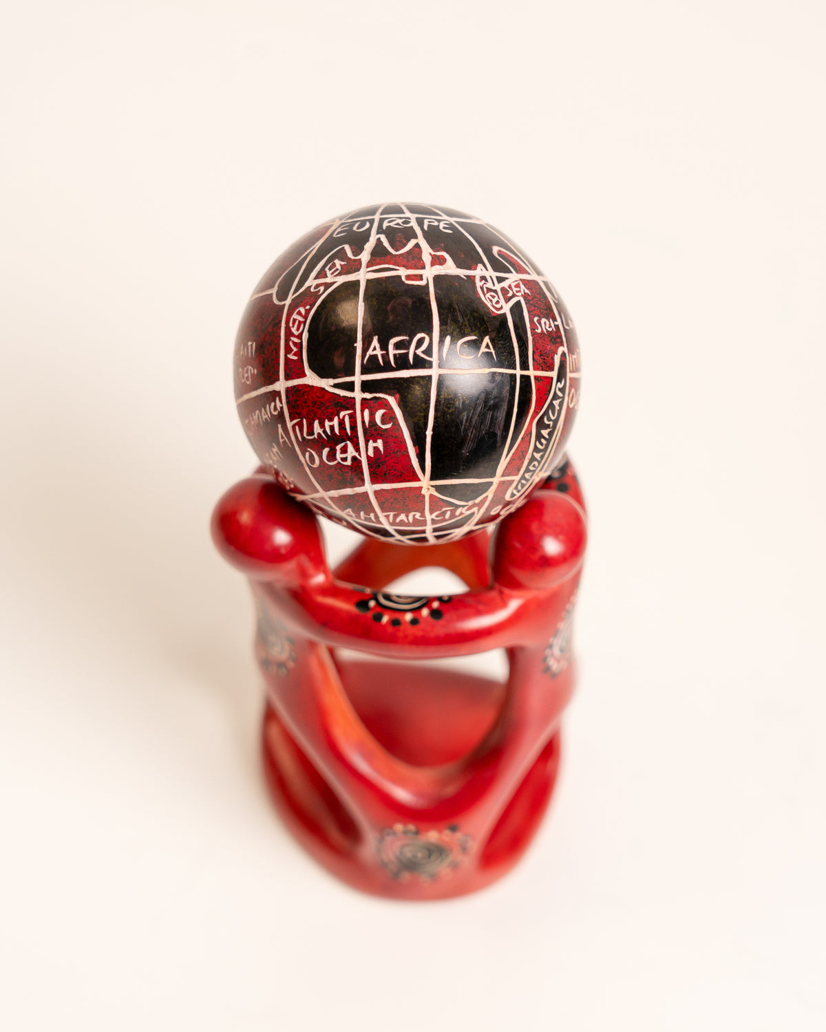 View from above of the black and red soapstone globe, with Africa facing forward and linked red figures below.