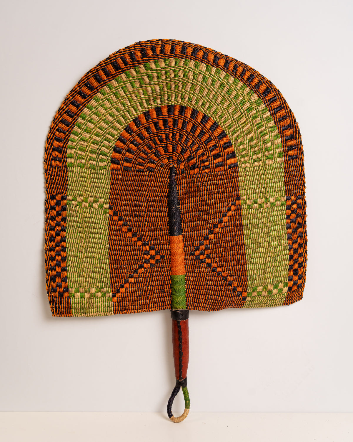 Large handwoven Bolga wall fan in orange, lime green and black with a leather-wrapped handle, Ghana