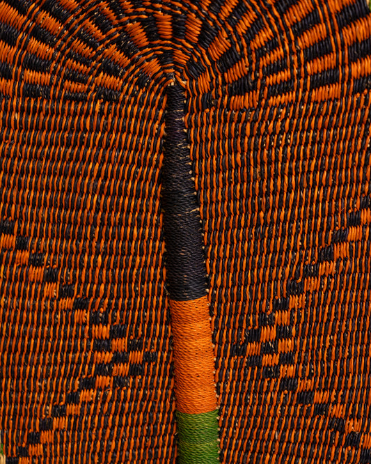 Close-up of the orange and black weave and leather-wrapped handle on a large handwoven Bolga wall fan