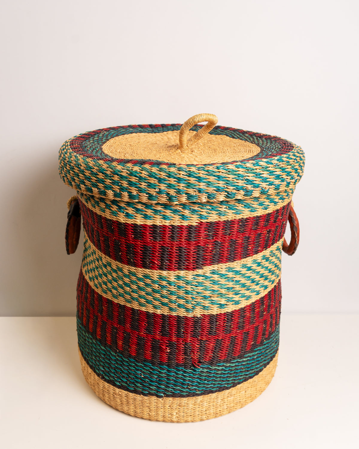 Top view of Bolga laundry basket with woven lid, red, teal and black stripe, handwoven elephant grass, Ghana