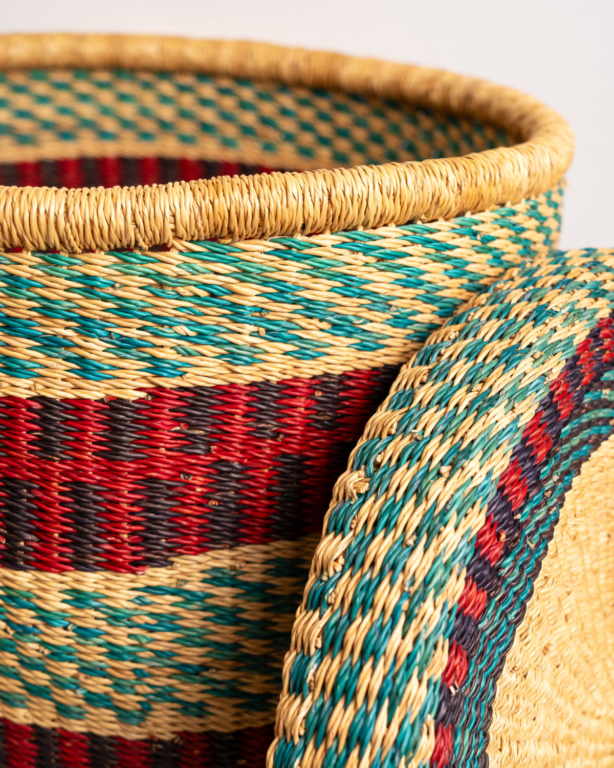 Close-up of handwoven elephant grass weave on Bolga laundry basket, red, teal and black stripe detail, Ghana