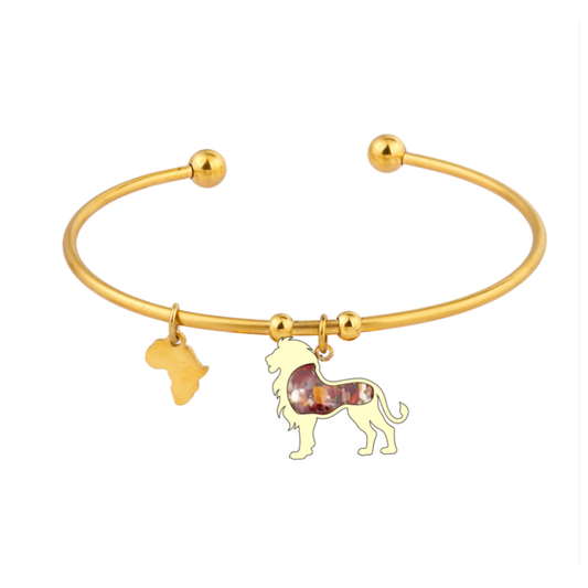 Gold-plated open cuff lion bangle with a lion charm set with mookaite inlay and a small Africa-shaped charm, on a plain white background.