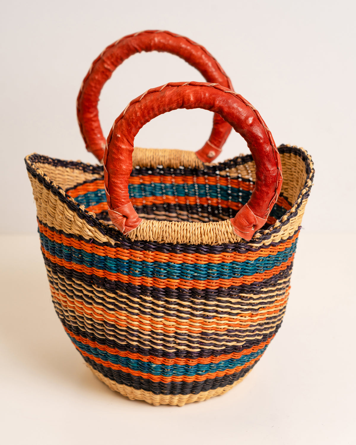 Small handwoven Bolga basket with leather handles, side view, made in Bolgatanga, Ghana